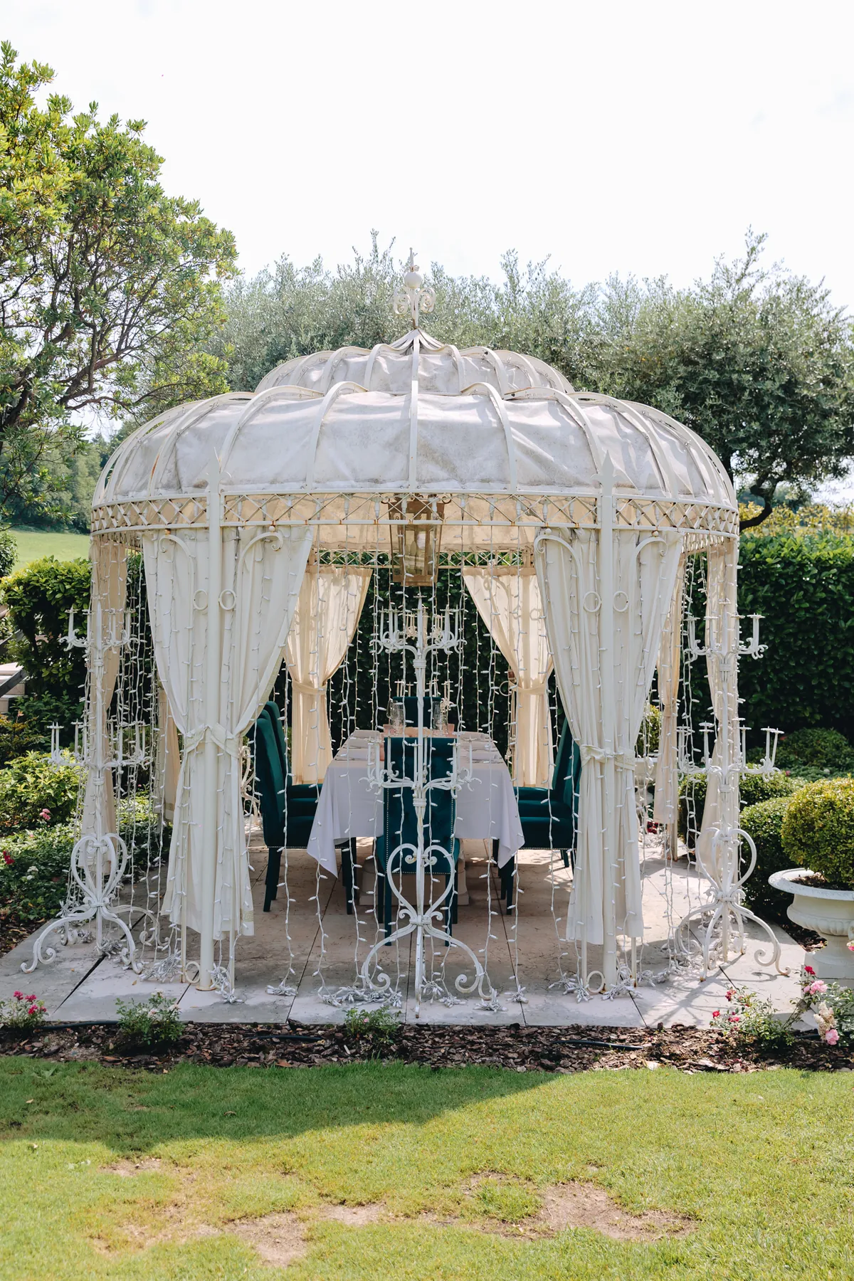 Il gazebo bianco nel giardino, con la tavola apparecchiata e le sedute blu