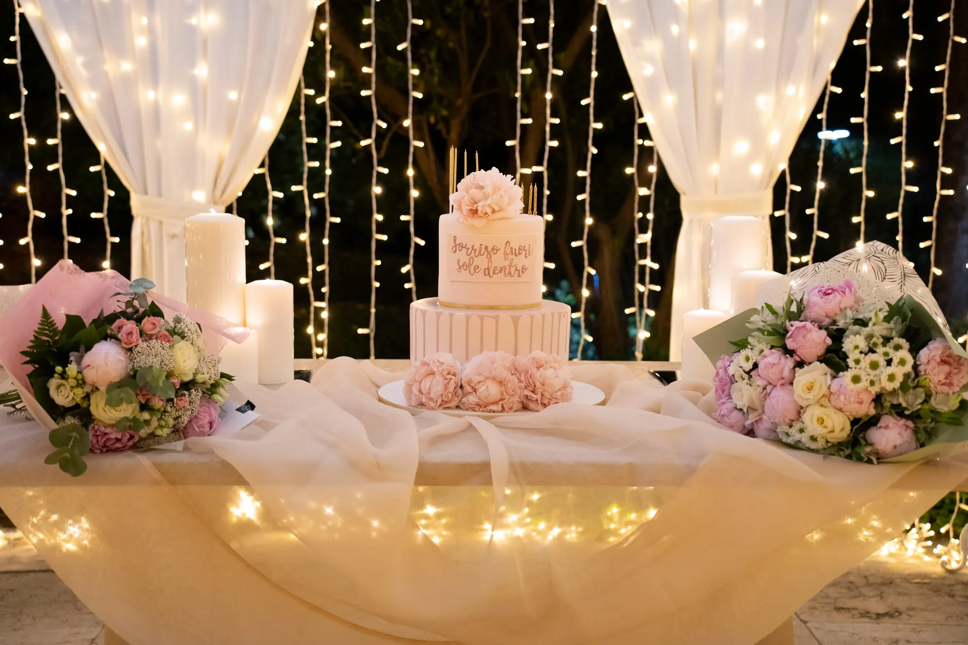 Una torta di compleanno fra fiori e luci nel gazebo