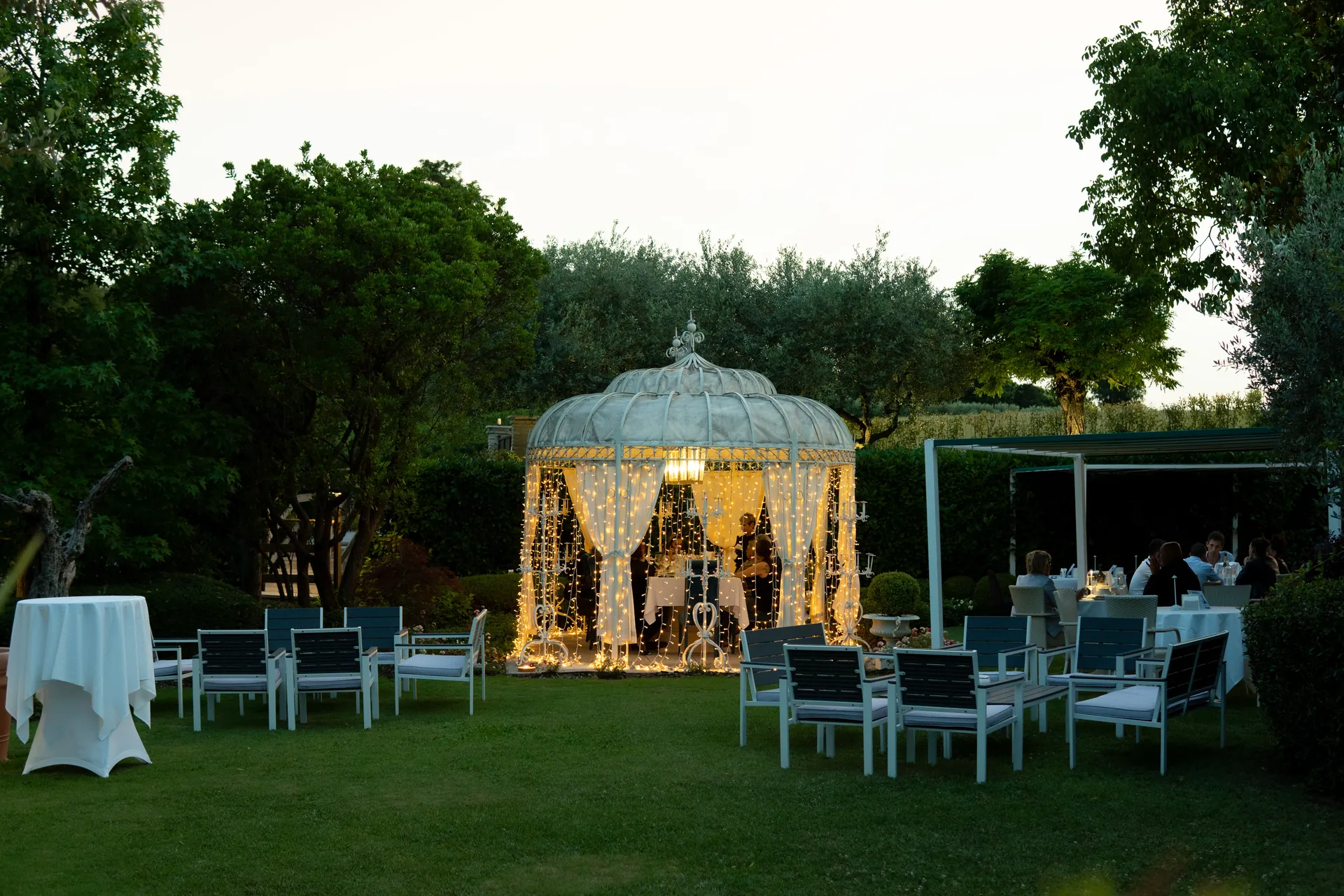 Il gazebo illuminato al tramonto, fra i tavoli e il verde del giardino