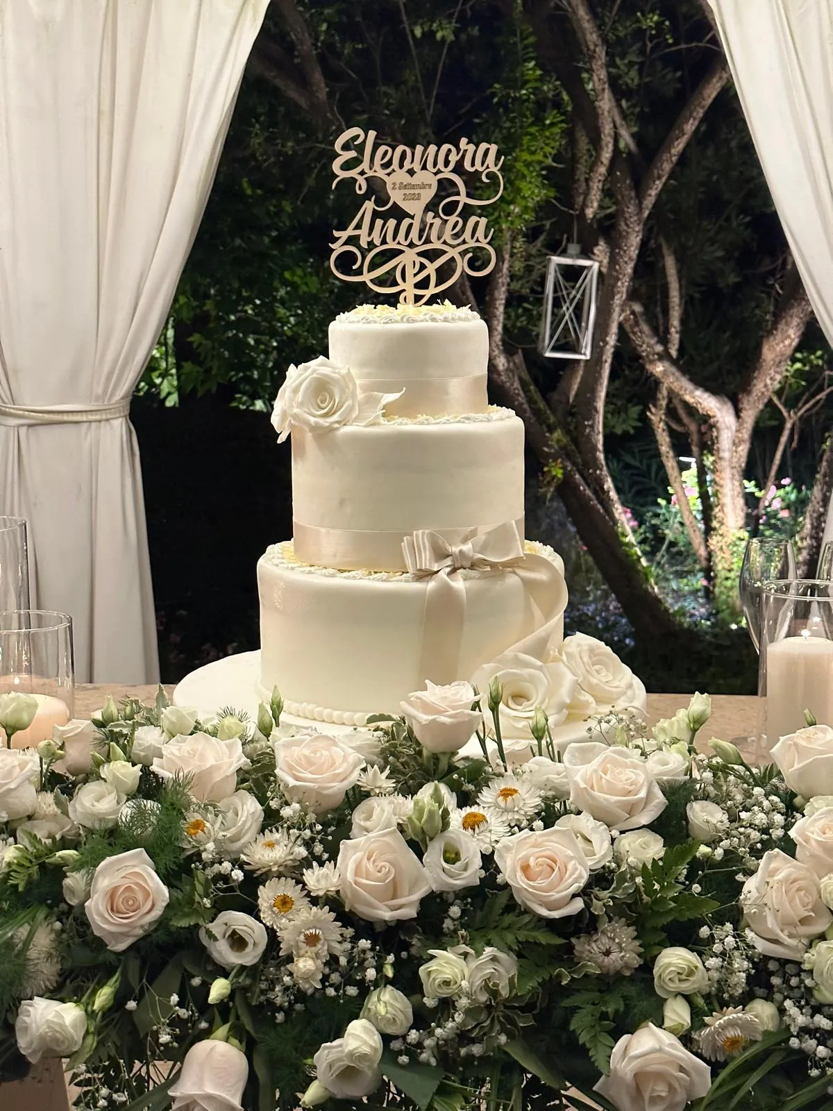 La torta nuziale fra fiori bianchi e luci nel gazebo