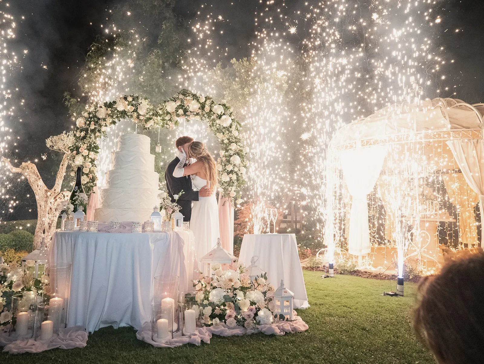 Gli sposi al taglio della torta, circondati dalle luci della festa
